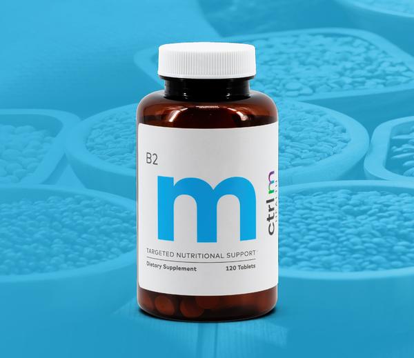 Picture of B2 supplement bottle with big blue “M” on it, blue gradient background with bowls of ingredients.